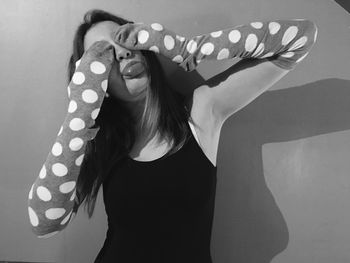 Woman wearing covering eyes with socks in hands against wall