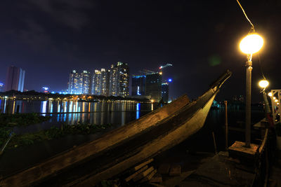 Scenic view of lake by illuminated buildings at night