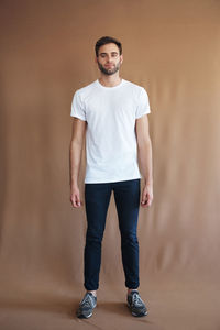 Full length of man standing against beige background