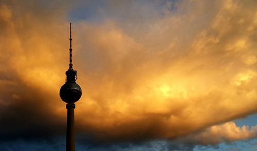 Low angle view of communications tower against cloudy sky