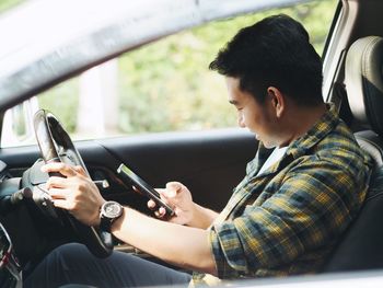 Smiling man using phone while driving car