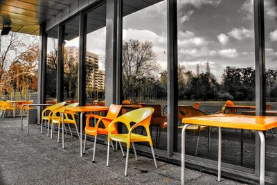 Chairs and table by trees against sky