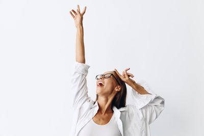 Young woman with arms raised against white background