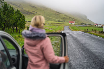 Rear view of woman driving car on road