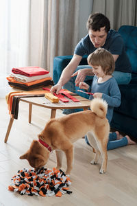 Cute preschooler boy and dad making diy snuffle mats for their pets, domestic cat and dog