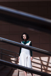 Portrait of woman standing against railing