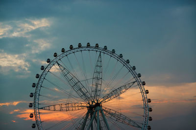 Low angle view of ferris wheel against sky at sunset