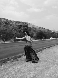 Woman with umbrella on road against sky