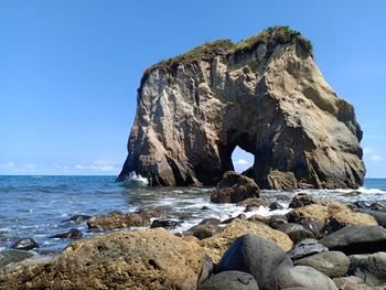 Rock formation on beach against clear blue sky