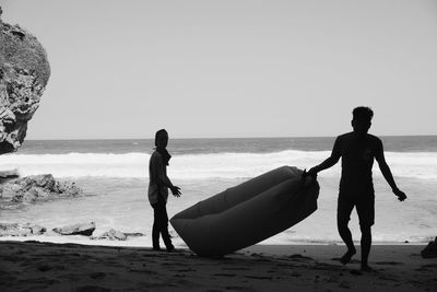 People on beach against clear sky