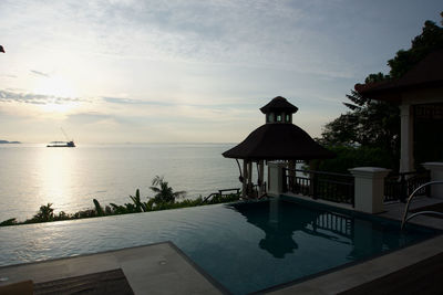 Swimming pool by sea against sky during sunset