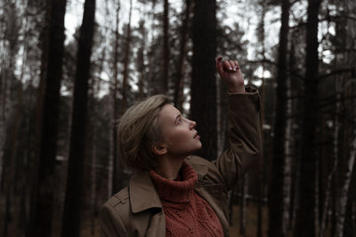 Young woman looking up while standing in forest