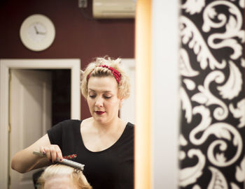 Mature woman brushing hair while standing at home