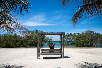 Woman sitting on swing at beach
