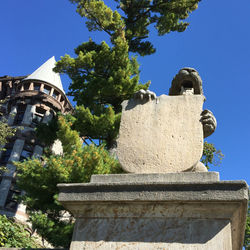 Low angle view of statue by building against sky