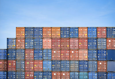 Stack of building by pier against blue sky