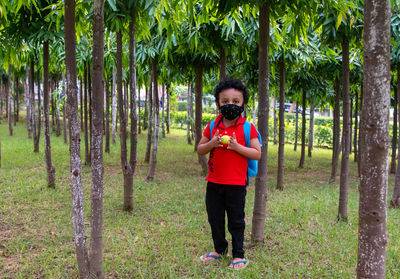 Full length of boy with mask standing by trees in forest