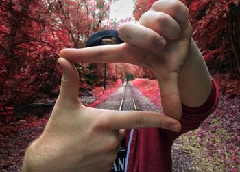 Digital composite image of railroad track seen through man hands