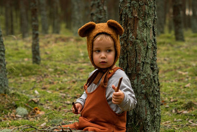 Toddler baby boy in bear bonnet sitting in the woods