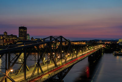 Illuminated bridge over river against sky at night