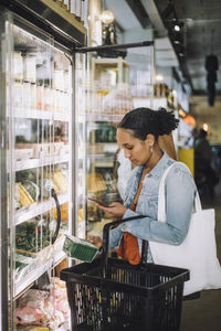 Female customer photographing package at organic delicatessen