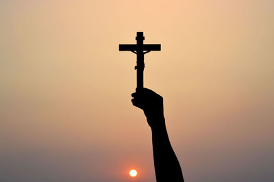 Silhouette cross against sky during sunset