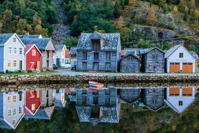 Houses by river against buildings