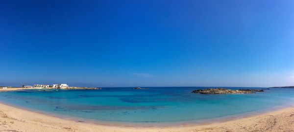 Scenic view of beach against clear blue sky