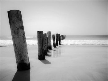 Wooden posts on beach against sky