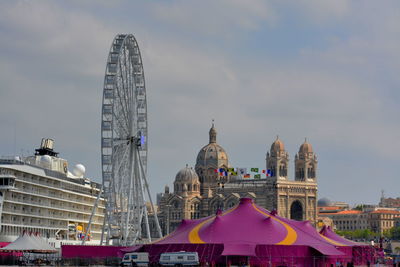 Low angle view of ferris wheel against buildings in city