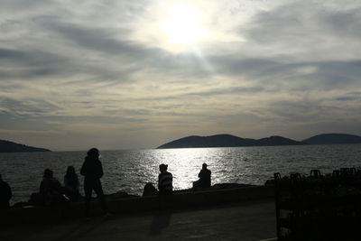 Silhouette people on beach against sky during sunset