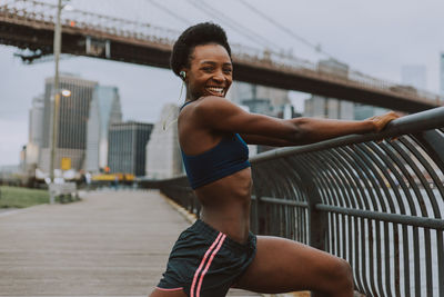 Woman exercising on bridge in city