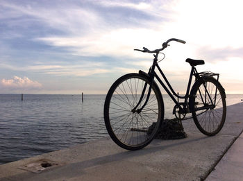 Bicycle by sea against sky