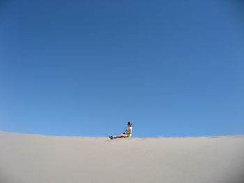 Man on desert against clear blue sky