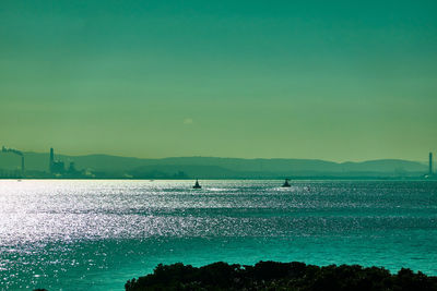 Scenic view of sea and ship against clear sky during sunrise