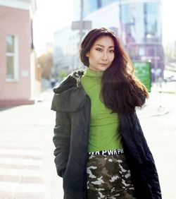 Portrait of young woman standing on street in city