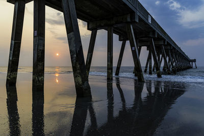 Reflection of pier on sea against sky during sunset