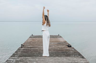 Full length of young woman standing against sea