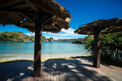 Thatched roofs on porch by beach during sunny day