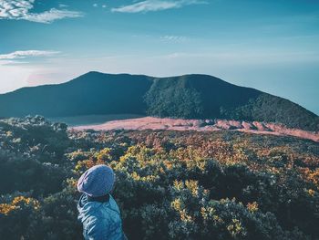 Rear view of woman looking at mountains against sky