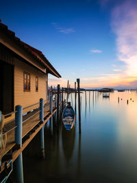 Wooden posts in canal by building against sky