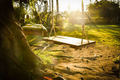 Wooden swings by tree at playground during sunset