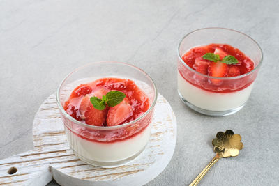 Sweet vanilla silky pudding dessert with strawberry sauce, sliced fresh strawberries and mint 