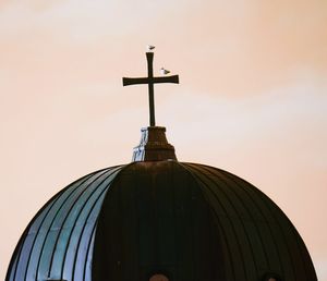 Low angle view of cross on building against sky during sunset