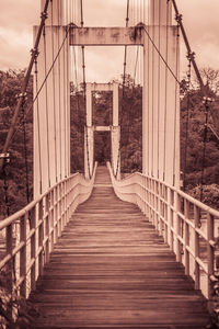 Footbridge over suspension bridge against sky