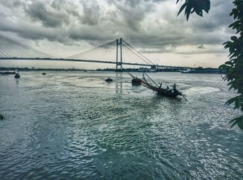 Suspension bridge over sea against sky