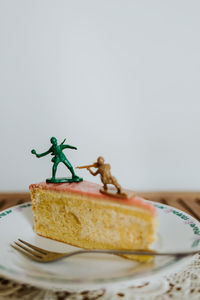 Close-up of dessert in plate with toy soldiers fighting on it against white background 
