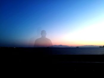 Silhouette woman standing by sea against clear sky during sunset