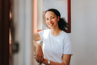 Portrait of a smiling young woman at window