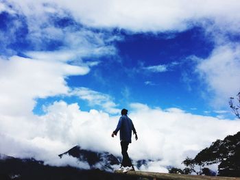 Low angle view of woman standing against cloudy sky